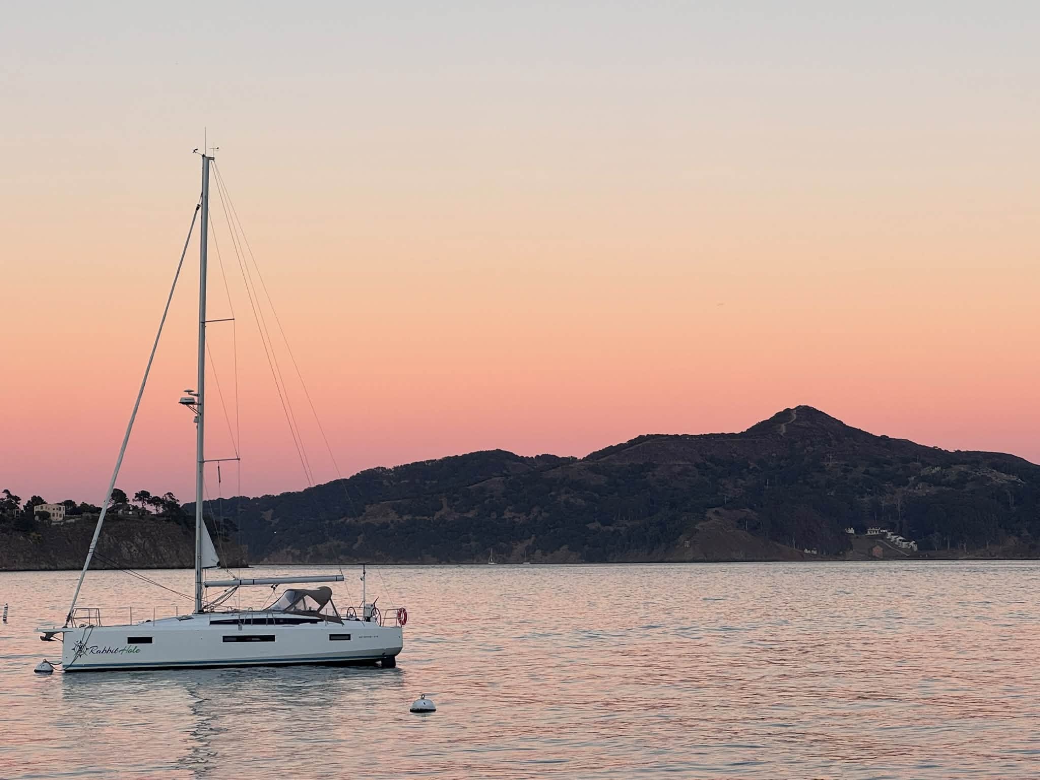 Sailboat anchored at sunset with mountains in the background