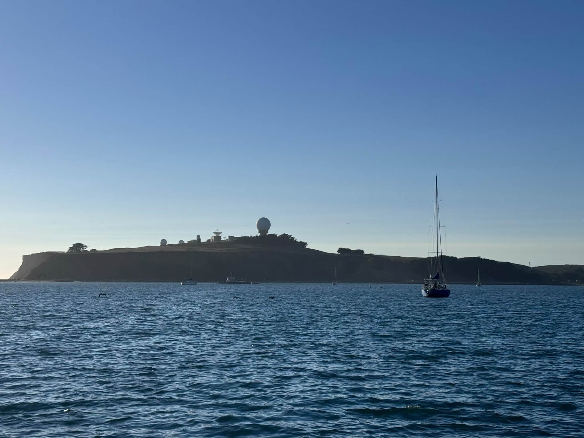 SV Rabbit Hole anchored near a coastal island fortress