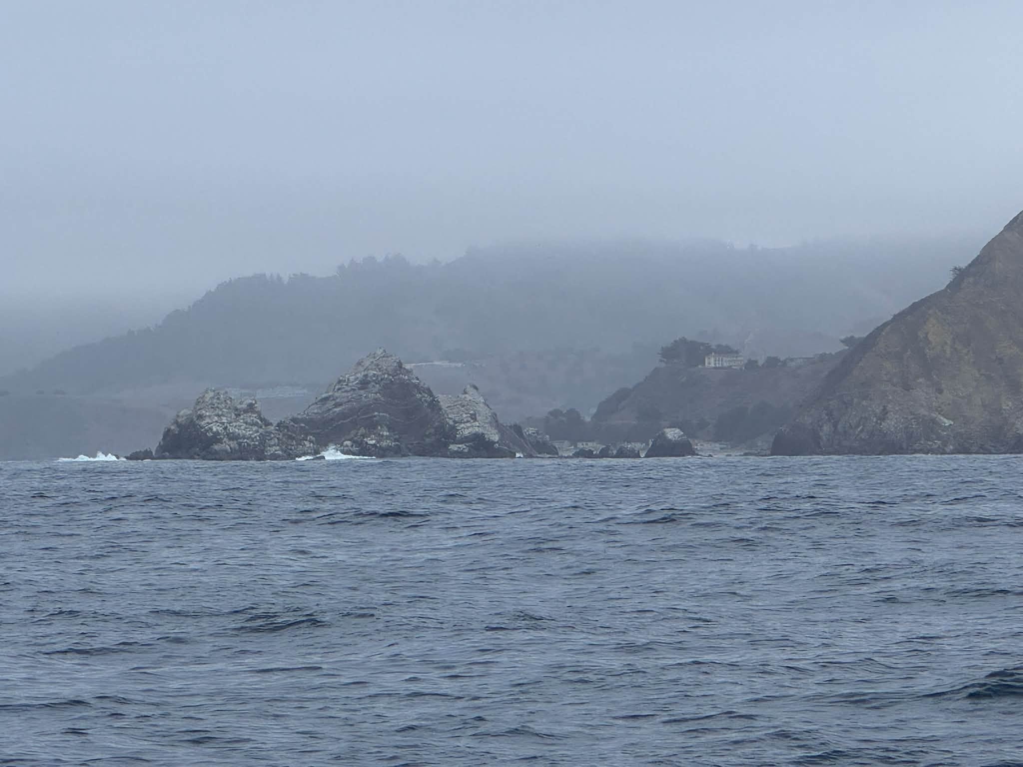 Misty coastal cliffs and rocky outcrops viewed from the water