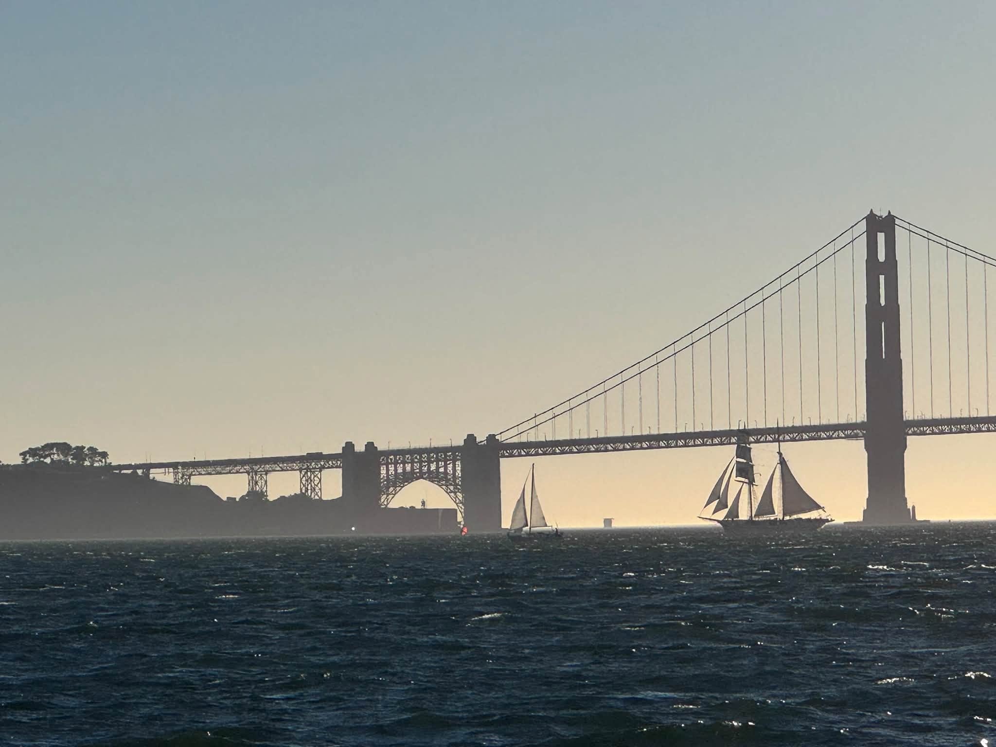 Sailboats silhouetted against the Golden Gate Bridge at sunset
